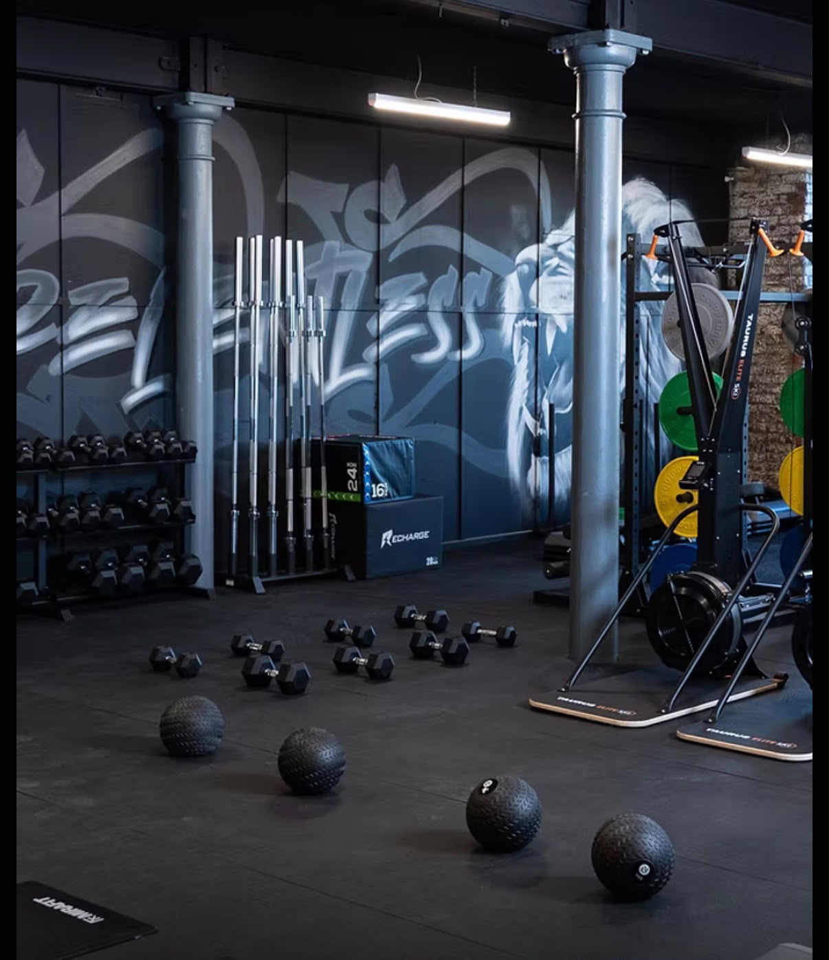 The training floor at Relentless Gym with dumbbells, medicine balls and graffiti artwork